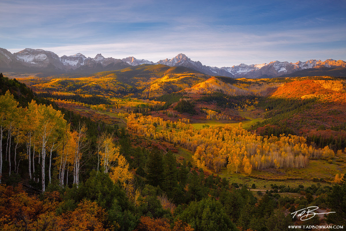 This Colorado fall photo depicts sunrise with warm light over Mount Sneffels with colorful fall foliage in the foreground