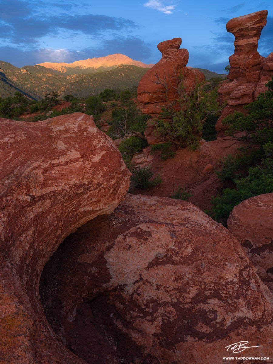 This Colorado photo depicts sunrise with a glow on Pike's Peak with colorful rock formations in the foreground.