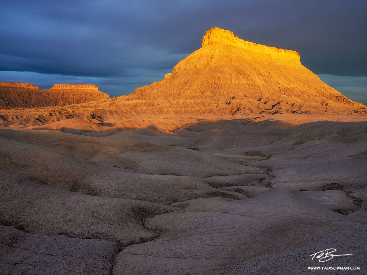 This desert photo depicts golden light illuminating Factory Butte