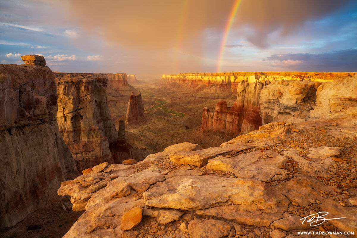 This Arizona desert photo depicts two rainbows extending into a scenic canyon at sunset