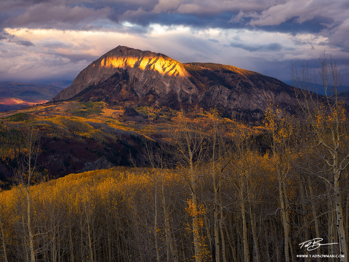 This Colorado fall photo depicts moody skies and a liver of sunshine on Marcellina Peak along with colorful fall foliage situated...