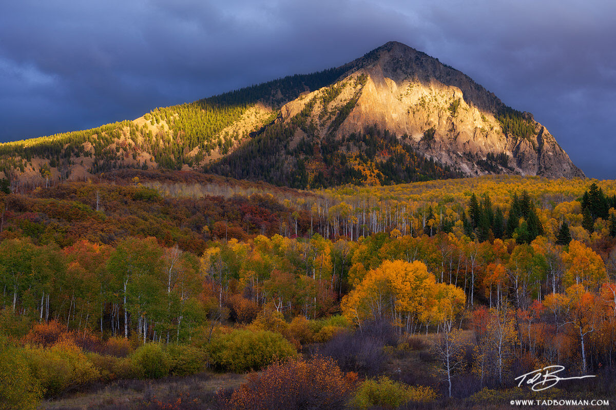 This Colorado mountain photo depicts gold light filtering through the clouds on Marcellina Mountain with colorful fall foliage...