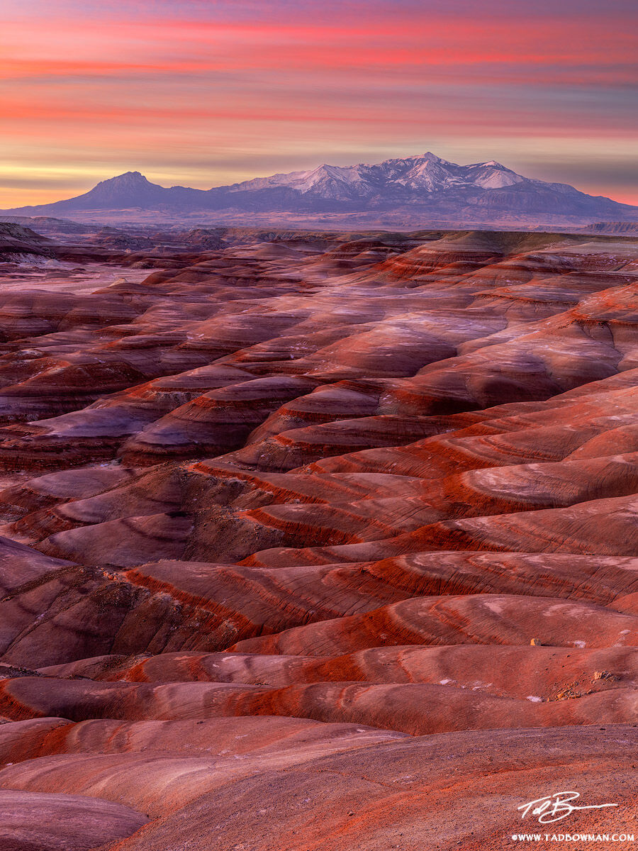 This Utah desert photo depicts sunrise over the Henry Mountains with colorful bentonite hills in the foreground