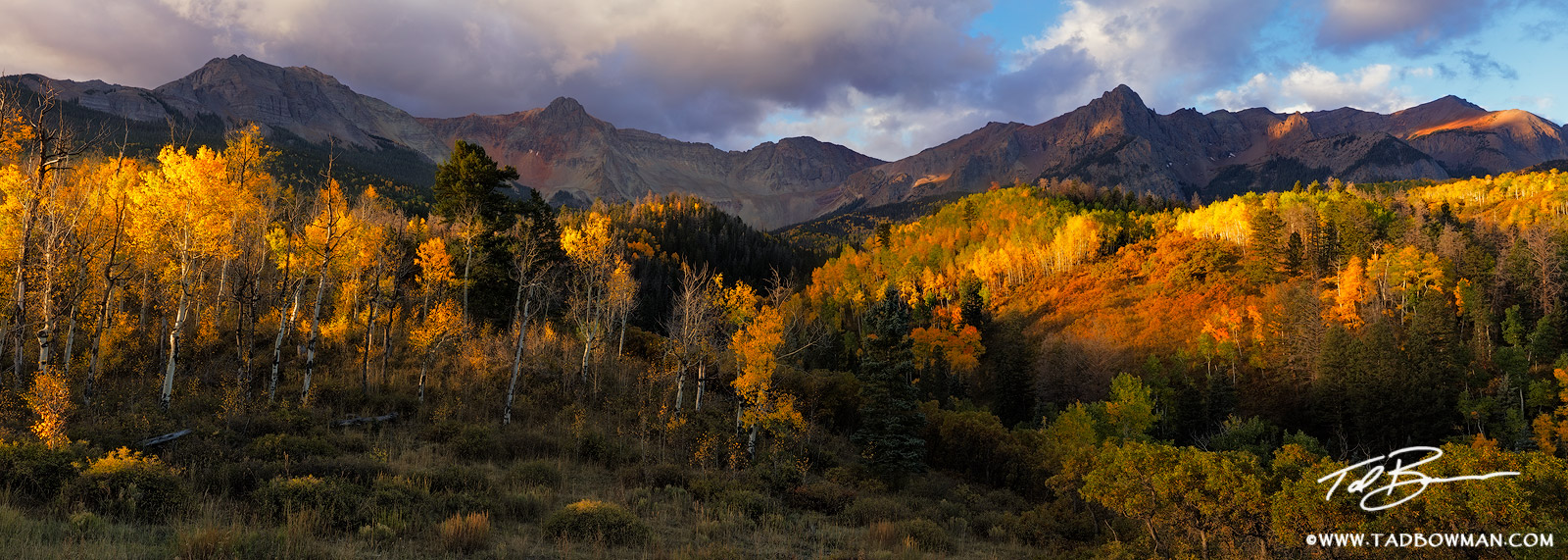 This Colorado fall mountain photo depicts stormy conditions over mountain peaks in the Sneffels Wilderness with sunlight painting...