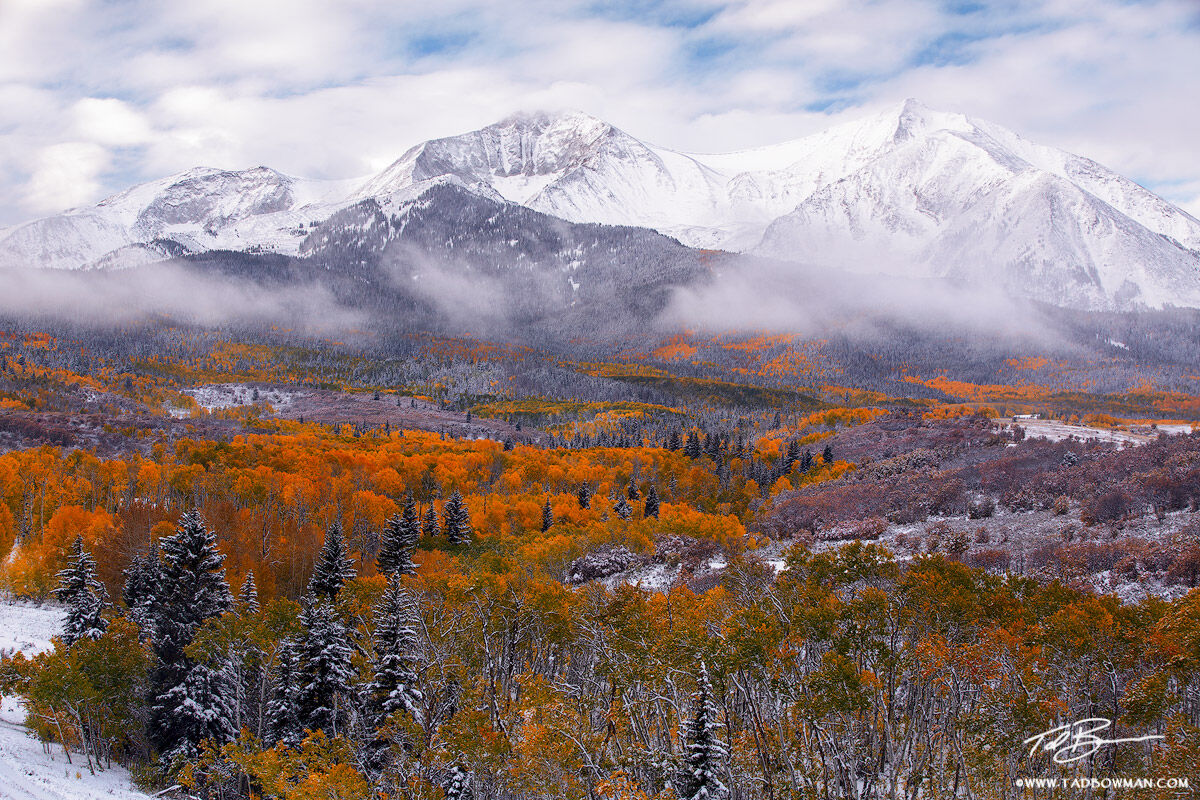 This fall Colorado photo depicts clouds lingering around Mount Sopris after a fresh snow with colorful aspen foliage in the foreground...