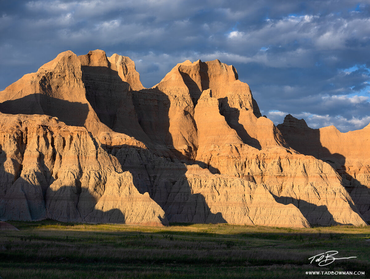Stone and Shadow Warm sunset light washes across steep, layered badlands cliffs in Badlands National Park, South Dakota, casting deep shadows...